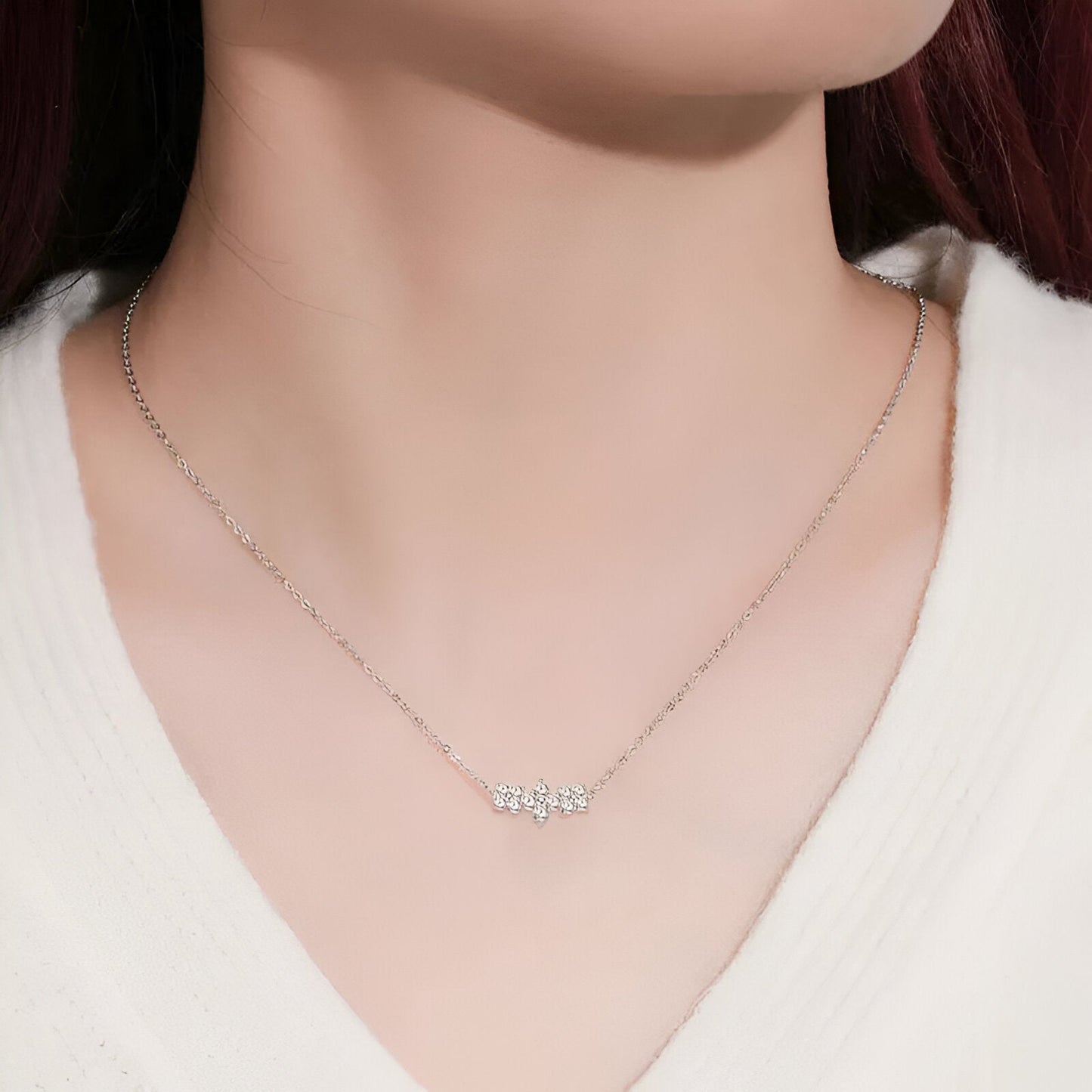 Pendentif trio de fleurs en argent 925 plaqué or blanc et diamants brillants porté au cou d'une femme vue de face.