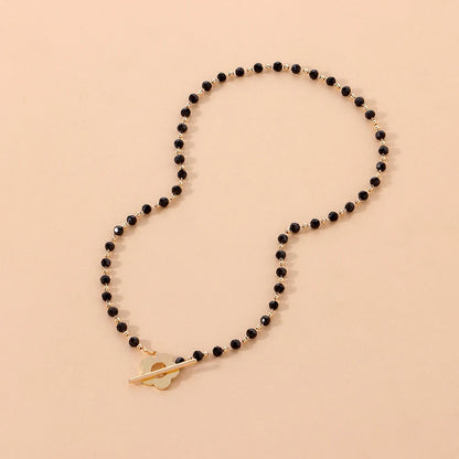 Collier ras-du-cou fleur de marguerite en plaqué or jaune et cristaux noirs en entier à plat.