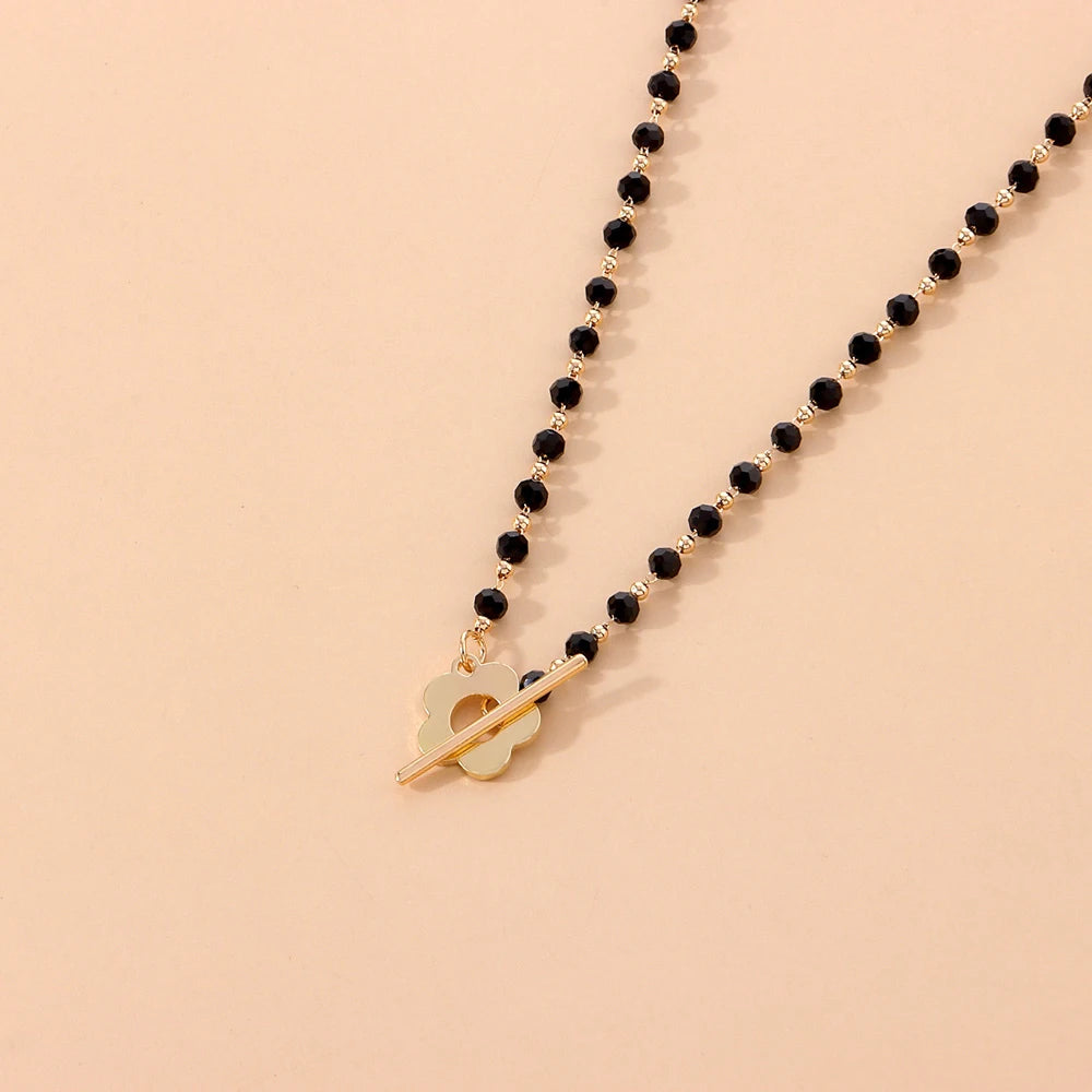 Collier ras-du-cou fleur de marguerite en plaqué or jaune et cristaux noirs vue de proche.