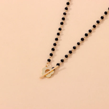 Collier ras-du-cou fleur de marguerite en plaqué or jaune et cristaux noirs vue de proche.