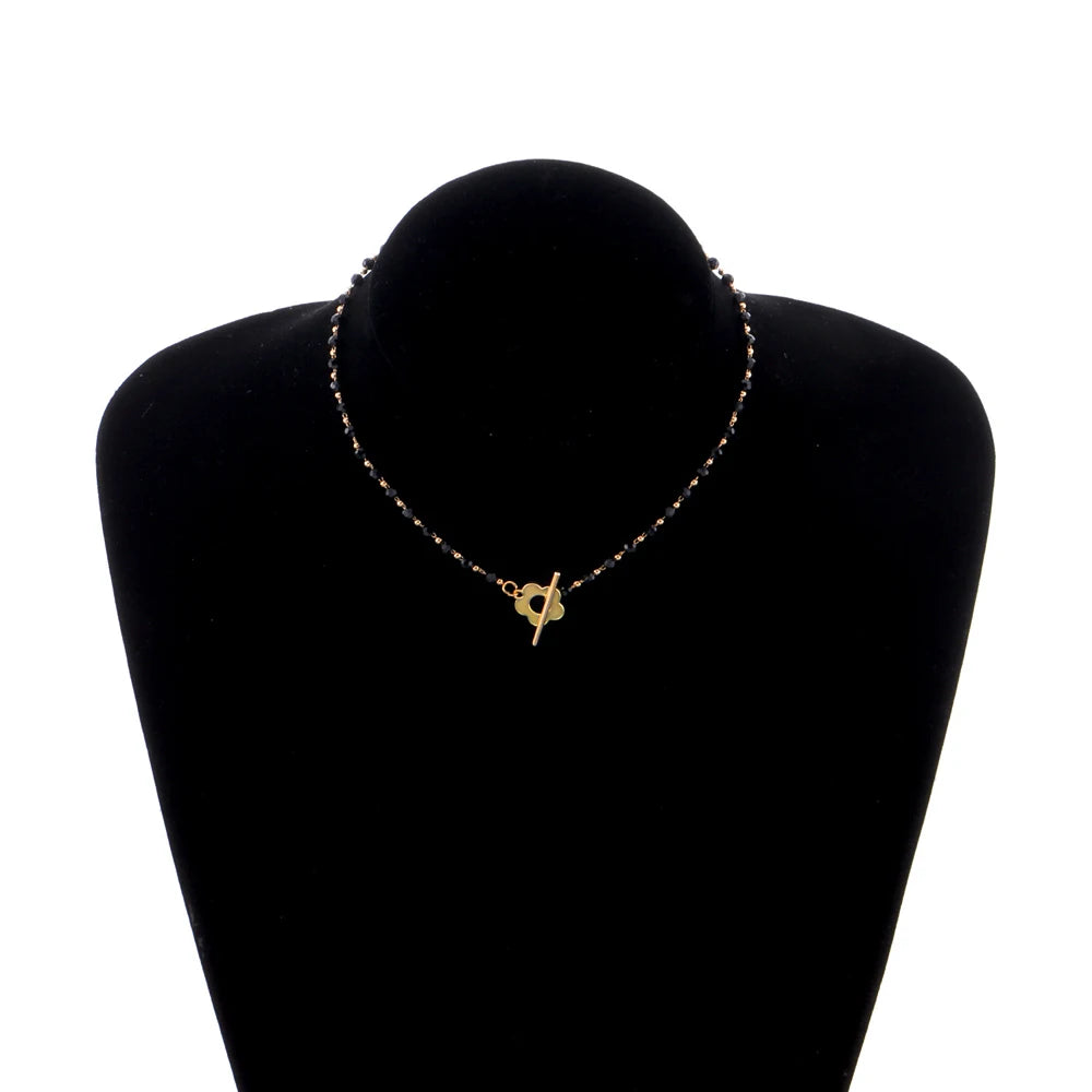 Collier ras-du-cou fleur de marguerite en plaqué or jaune et cristaux noirs porté par un mannequin.