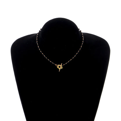 Collier ras-du-cou fleur de marguerite en plaqué or jaune et cristaux noirs porté par un mannequin.