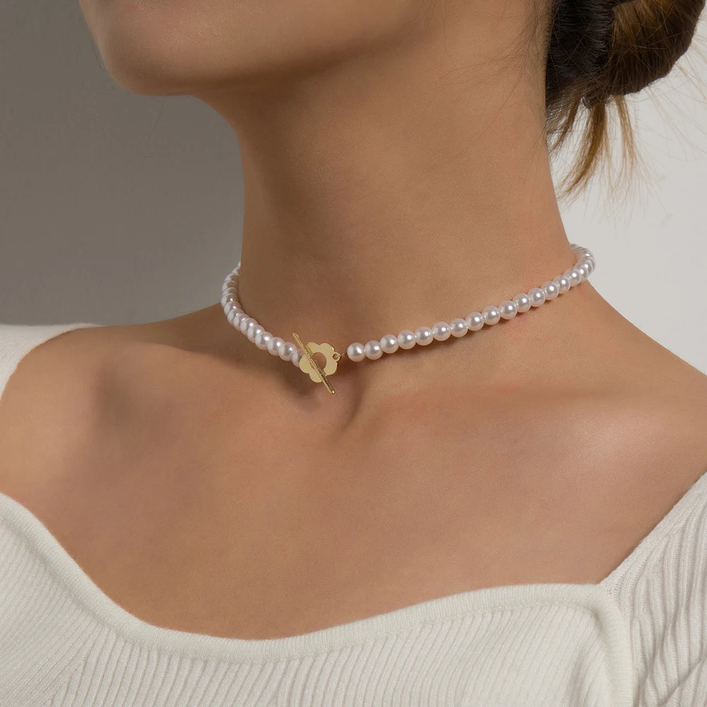 Ras-du-cou fleur de marguerite plaqué or jaune et perles naturelles nacrées porté au cou d'une femme vue de côté.