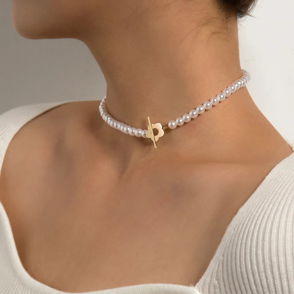Ras-du-cou fleur de marguerite plaqué or jaune et perles naturelles nacrées porté au cou d'une femme.