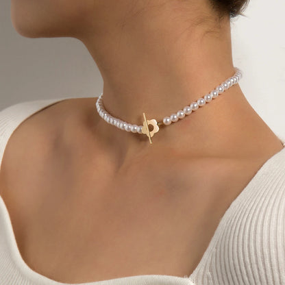 Ras-du-cou fleur de marguerite plaqué or jaune et perles naturelles nacrées porté au cou d'une femme.