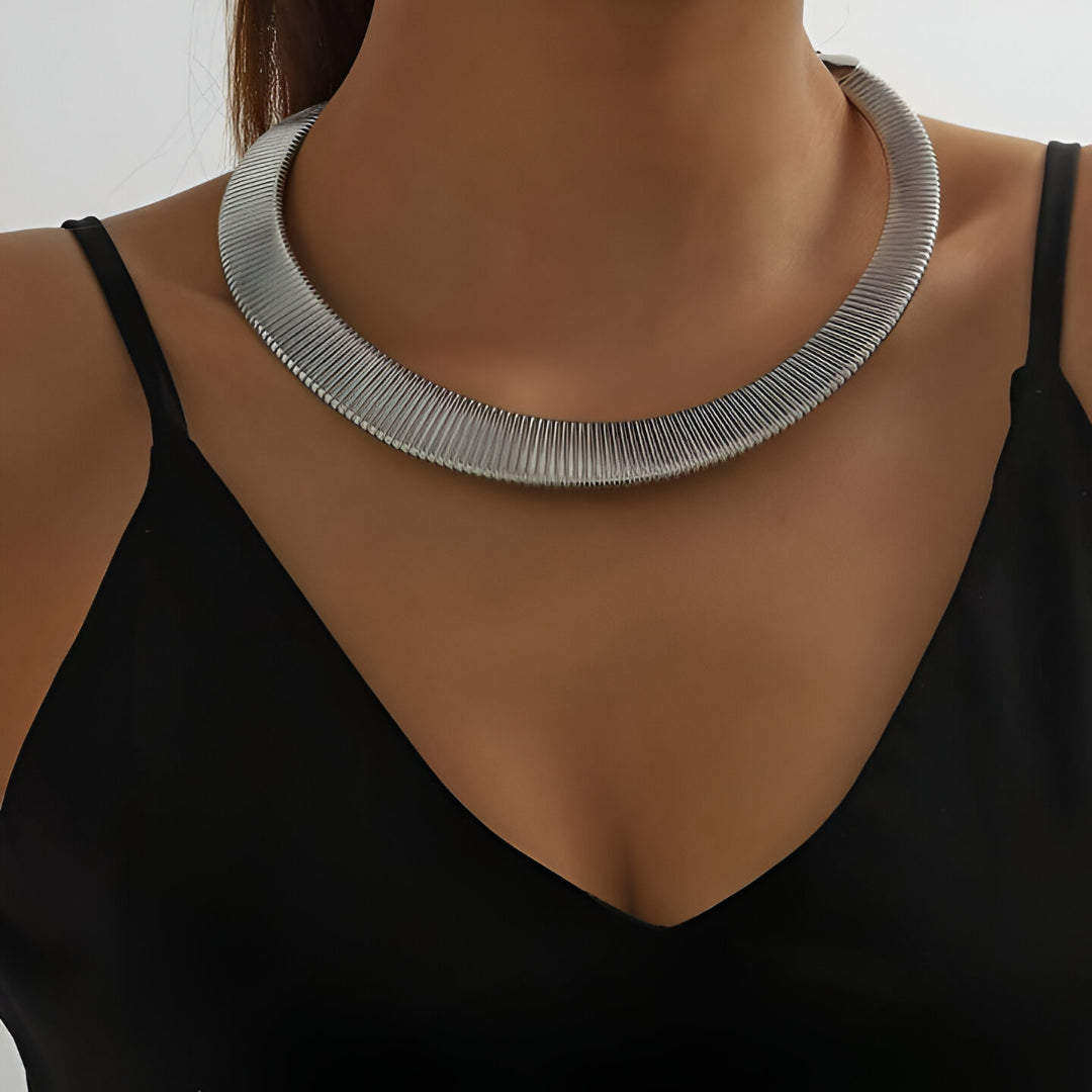 Collier choker torque en or blanc porté au cou d'une femme.