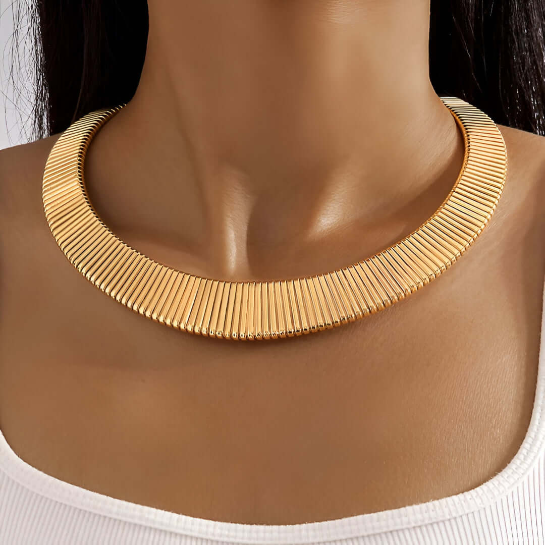 Collier choker torque en or jaune porté au cou d'une femme vue de face.