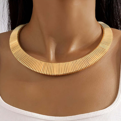 Collier choker torque en or jaune porté au cou d'une femme vue de face.
