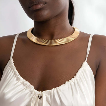 Collier choker torque en or jaune porté au cou d'une femme.