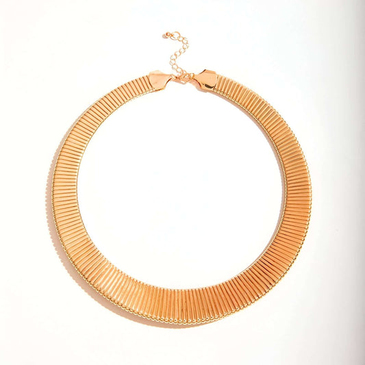 Collier choker torque en or jaune sur fond blanc.