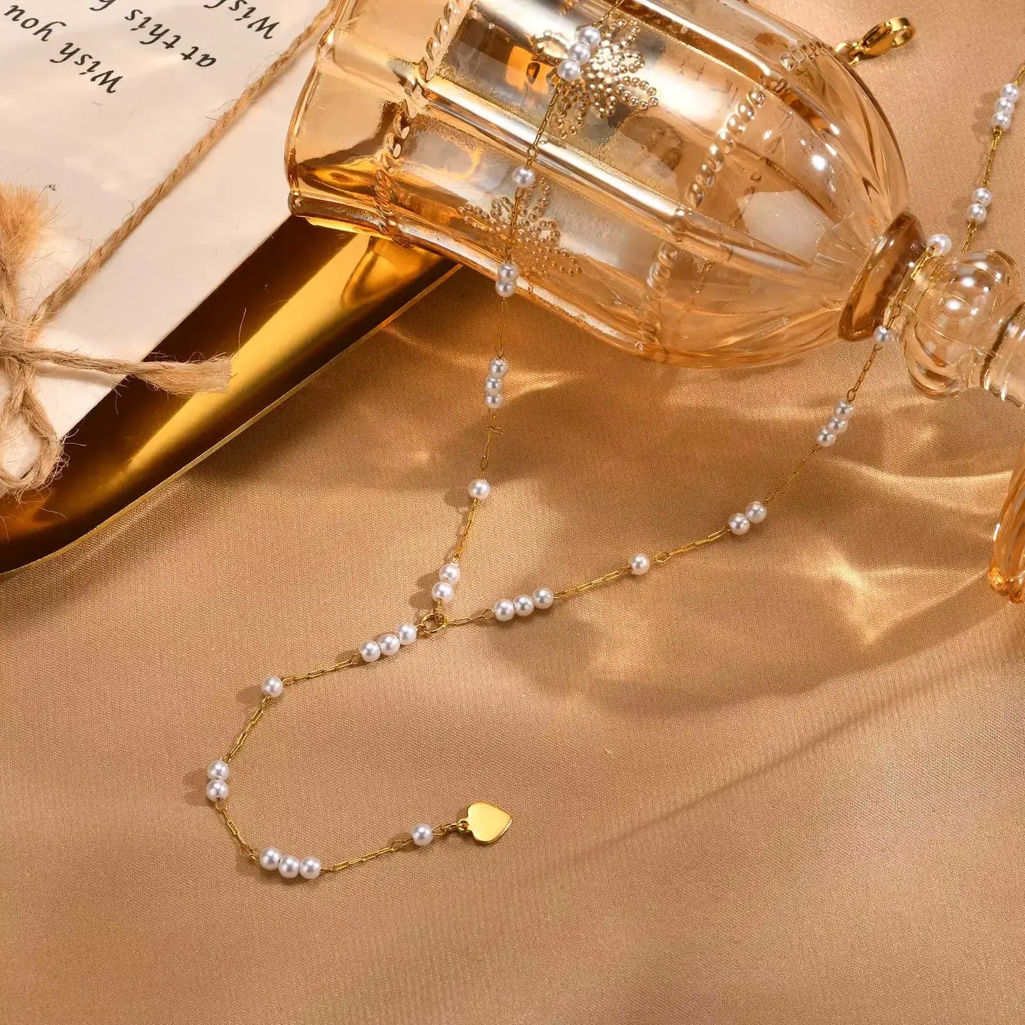 Collier sautoir fantaisie en acier doré orné de perles posé.