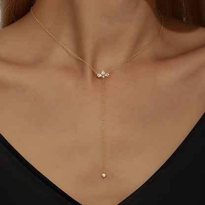 Sautoir fleur de lys Evenis en argent 925 plaqué or jaune et diamants porté au cou d'une femme vue de proche.
