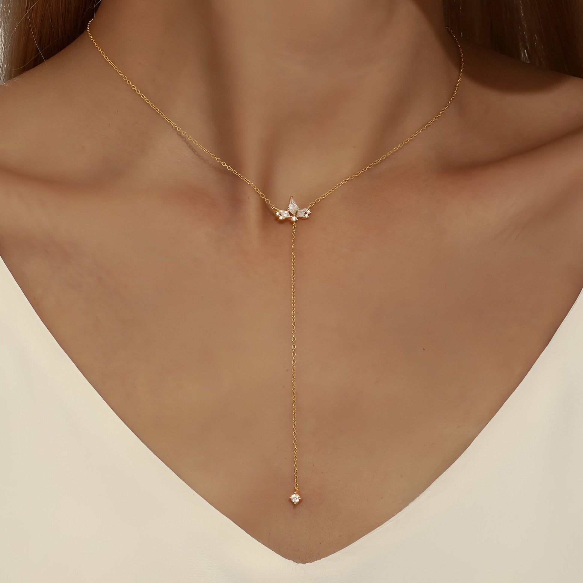 Sautoir fleur de lys Evenis en argent 925 plaqué or jaune chaleureux et diamants porté au cou d'une femme vue de face.