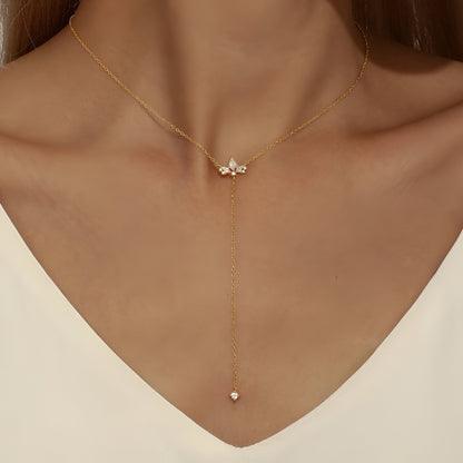 Sautoir fleur de lys Evenis en argent 925 plaqué or jaune chaleureux et diamants porté au cou d'une femme vue de face.