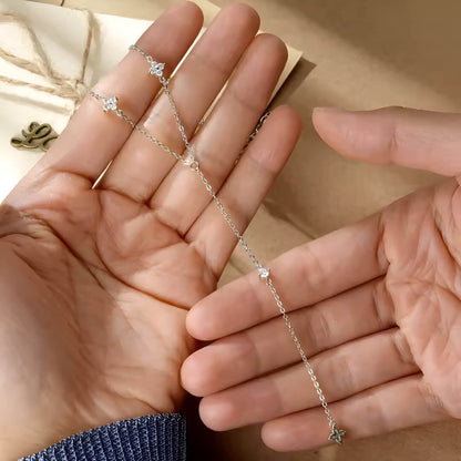 Sautoir floral chaîne argentée discrète en argent 925 plaqué or blanc délicat et moissanites à plat sur des mains de femme vue du dessus.