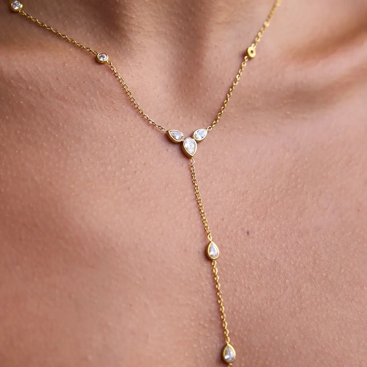 Sautoir goutte d'eau en acier inoxydable plaqué or jaune et diamants naturels porté au cou d'une femme vue de proche.