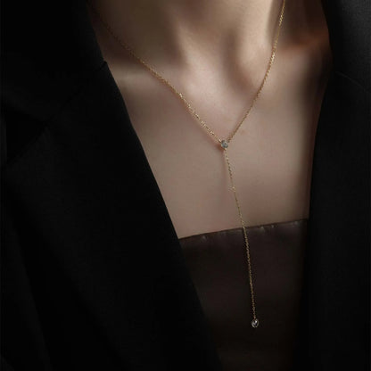 Sautoir long pendentif en argent 925 plaqué or jaune lumineux et diamants en zircon porté au cou d'une femme.