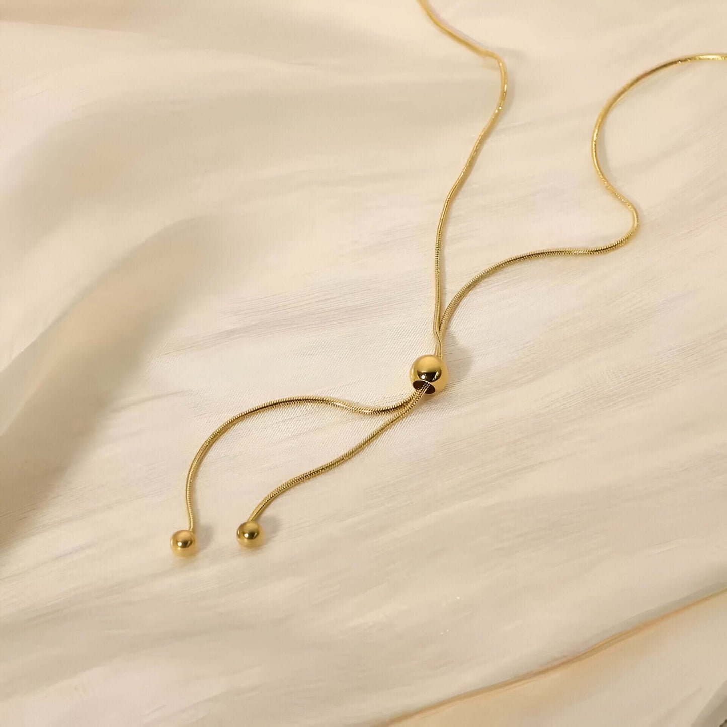 Sautoir perle synthetique amovible en acier doré orné de perle amovible à plat.