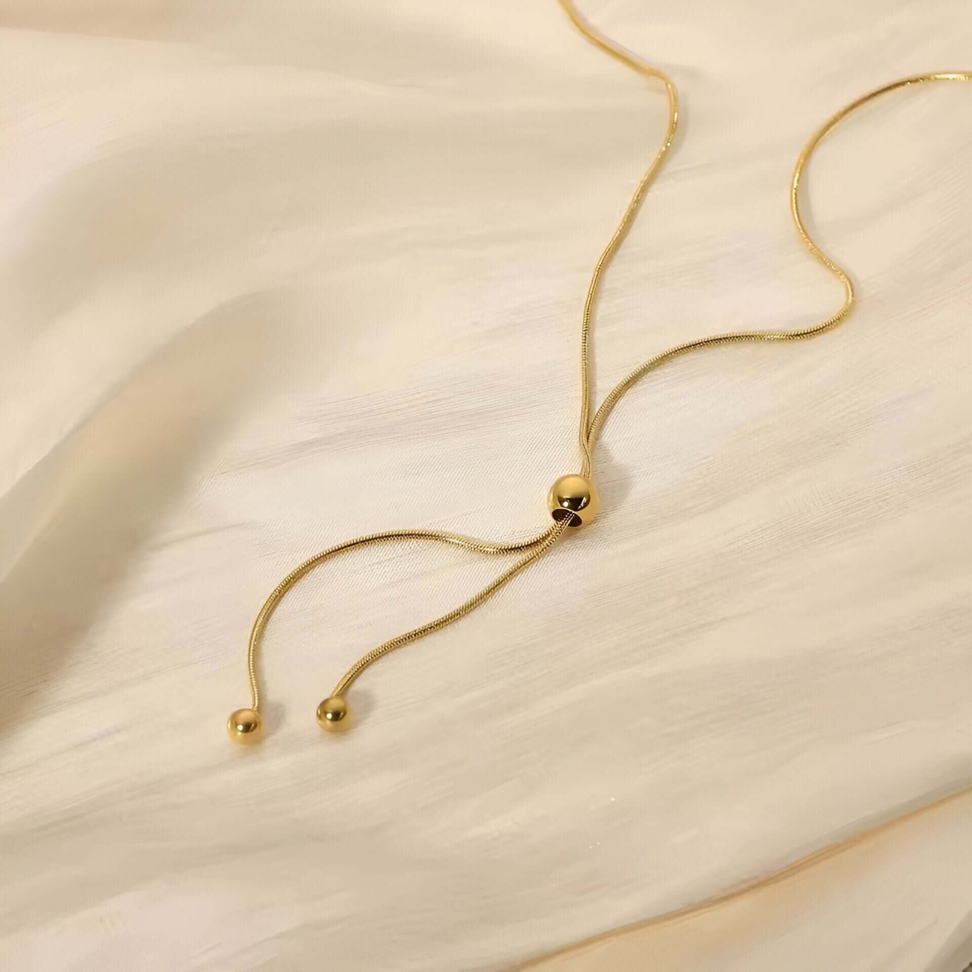 Sautoir perle synthetique amovible en acier doré orné de perle amovible à plat.